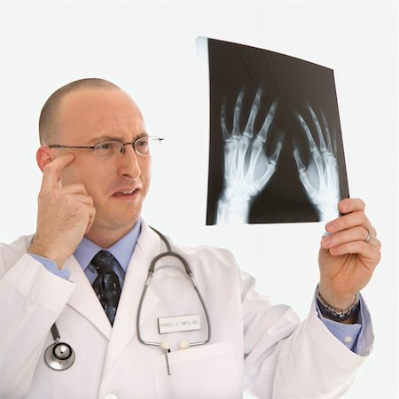 simsearch:400-04552598,k - Caucasian mid adult male physician holding up hand xrays looking perplexed. Foto de stock - Super Valor sin royalties y Suscripción, Código: 400-03926380