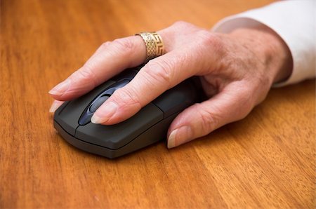 Older woman's hand using a wireless computer mouse. Focus is on the front of the mouse / end of the fingers. Stock Photo - Budget Royalty-Free & Subscription, Code: 400-03926704