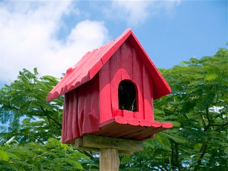 Red birdhouse against a background of blue sky and green trees Stock Photo - Budget Royalty-Free & Subscription, Code: 400-03928076