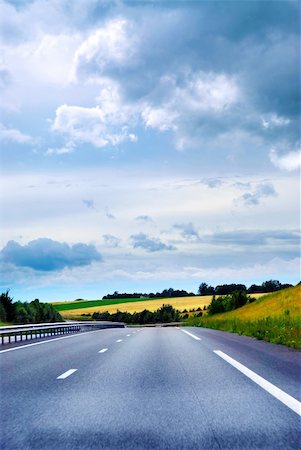 simsearch:400-05348671,k - Empty road among fields with blue cloudy sky Stock Photo - Budget Royalty-Free & Subscription, Code: 400-03928425