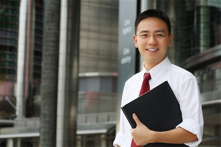 simsearch:6109-06002735,k - Good looking asian business man smiling with folder in hand. Stock Photo - Budget Royalty-Free & Subscription, Code: 400-03928899