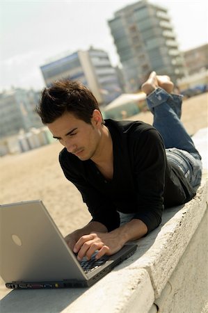 fabthi (artist) - Relaxed young man wearing casual shirt uses a notebook on the beach Foto de stock - Super Valor sin royalties y Suscripción, Código: 400-03929110