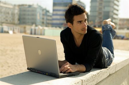 Attractive young man working at the beach with a laptop Stock Photo - Budget Royalty-Free & Subscription, Code: 400-03929111