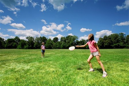 Two young girls playing with a flying disc in a sunny field on a beautiful summer day. Foto de stock - Royalty-Free Super Valor e Assinatura, Número: 400-03920672