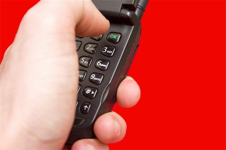 simsearch:400-04558697,k - A hand dialing a mobile phone on a red backround Stockbilder - Microstock & Abonnement, Bildnummer: 400-03920717