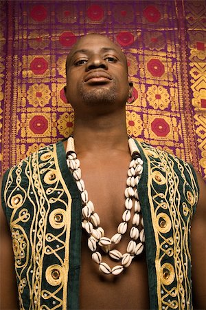 embroidery for male clothes - Low angle portrait of African-American mid-adult man wearing embroidered African vest and beads. Stock Photo - Budget Royalty-Free & Subscription, Code: 400-03921216