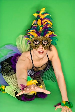 simsearch:614-01088532,k - Portrait of Hispanic woman in Mardi Gras type costume and mask kneeling on floor with hand reaching out against green background. Photographie de stock - Aubaine LD & Abonnement, Code: 400-03921900