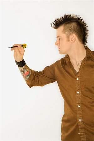 Side view of Caucasian man with mohawk holding and aiming dart against white background. Stock Photo - Budget Royalty-Free & Subscription, Code: 400-03921923