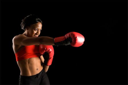 female stomach punching - African American young adult woman wearing boxing gloves throwing punch. Foto de stock - Super Valor sin royalties y Suscripción, Código: 400-03921999