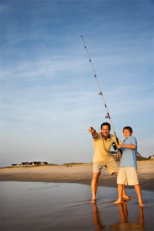 simsearch:400-04953081,k - Caucasian mid-adult man shore fishing on beach with pre-teen boy and pointing. Foto de stock - Royalty-Free Super Valor e Assinatura, Número: 400-03923412