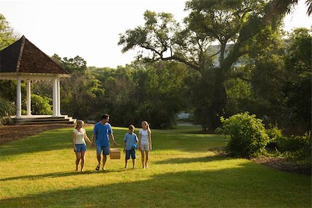 simsearch:400-04953081,k - Caucasian family of four walking in park carrying picnic basket. Foto de stock - Royalty-Free Super Valor e Assinatura, Número: 400-03923425