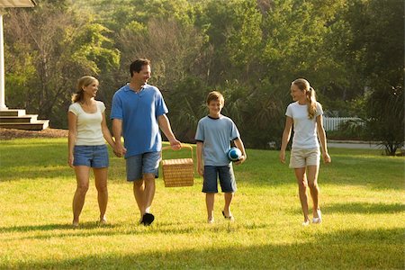 simsearch:400-04953081,k - Caucasian family of four walking in park carrying picnic basket. Foto de stock - Royalty-Free Super Valor e Assinatura, Número: 400-03923426