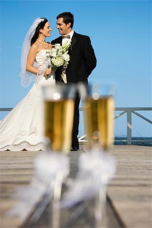 simsearch:400-03923118,k - Pair of flute glasses of champagne with Caucasian bride and groom in background. Fotografie stock - Microstock e Abbonamento, Codice: 400-03923444