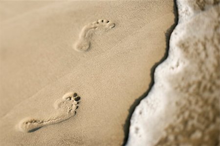 simsearch:400-03923118,k - Footprints in sand next to wave. Fotografie stock - Microstock e Abbonamento, Codice: 400-03923547