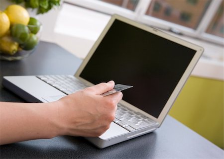 A young female making an online purchase from her kitchen. Stock Photo - Budget Royalty-Free & Subscription, Code: 400-03934692