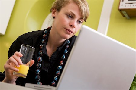 family eating computer - A young woman uses the computer in the kitchen while enjoying a glass of juice. The model is looking at the computer. Stock Photo - Budget Royalty-Free & Subscription, Code: 400-03935736