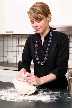 simsearch:649-06845216,k - A young woman makes bread on the counter at home in the kitchen. Photographie de stock - Aubaine LD & Abonnement, Code: 400-03935845