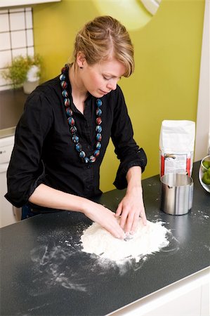 simsearch:649-06845216,k - A young woman makes bread on the counter at home in the kitchen. Photographie de stock - Aubaine LD & Abonnement, Code: 400-03935842