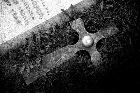 A black and white photograph of a cross, next to a tombstone. Stockbilder - Microstock & Abonnement, Bildnummer: 400-03936280