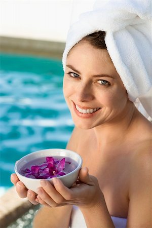 simsearch:400-03940673,k - Caucasian mid-adult woman wearing towel around head and body holding bowl of purple orchids next to pool. Stock Photo - Budget Royalty-Free & Subscription, Code: 400-03937630