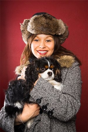 simsearch:400-04446240,k - Young adult Caucasian woman wearing fur hat holding King Charles Spaniel in arms and smiling at viewer. Foto de stock - Super Valor sin royalties y Suscripción, Código: 400-03937664