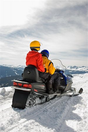 simsearch:400-03944669,k - Man and woman riding on snowmobile in snowy mountainous terrain. Photographie de stock - Aubaine LD & Abonnement, Code: 400-03937776