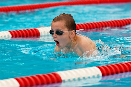 Action photo of a young boy wearing goggles swimming in a pool. Stock Photo - Budget Royalty-Free & Subscription, Code: 400-03938689