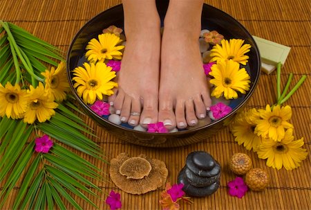 smelling feet - Spa treatment with aromatic gerbera daisies, healing stones, olive oil soaps and mineral water Stock Photo - Budget Royalty-Free & Subscription, Code: 400-03944394