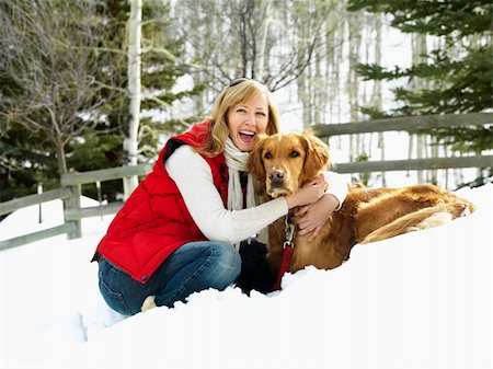 simsearch:400-03944669,k - Woman hugging dog and smiling in snow covered Colorado landscape. Photographie de stock - Aubaine LD & Abonnement, Code: 400-03944674