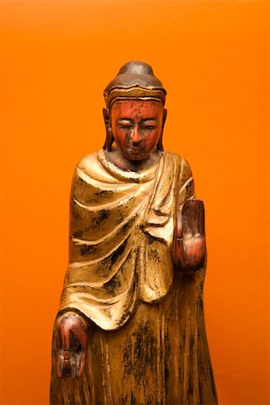 simsearch:400-03944899,k - Wooden Buddha statue gesturing with one hand up and one hand down against orange wall. Stock Photo - Budget Royalty-Free & Subscription, Code: 400-03944898