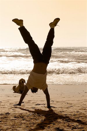 Dog watching a boy doing handstand on the beach Stock Photo - Budget Royalty-Free & Subscription, Code: 400-03944982