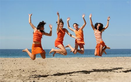 simsearch:6109-06195410,k - Four girls in orange clothes jumping on the beach Photographie de stock - Aubaine LD & Abonnement, Code: 400-03945541