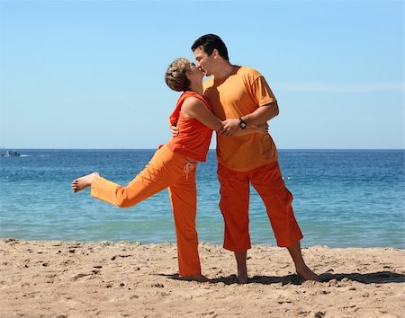 simsearch:400-06751687,k - Couple in orange clothes kissing on the beach Stock Photo - Budget Royalty-Free & Subscription, Code: 400-03945575