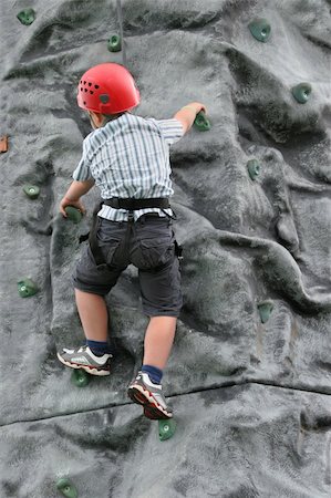 simsearch:400-03936239,k - Young boy climbing on a rock training face, wearing a safety harness and red helmet. Stockbilder - Microstock & Abonnement, Bildnummer: 400-03946278
