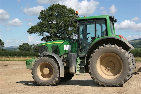 Green four wheel drive tractor standing idle on rough ground, with rural countryside to the rear and a blue sky with cumulus clouds. Stock Photo - Budget Royalty-Free & Subscription, Code: 400-03946279