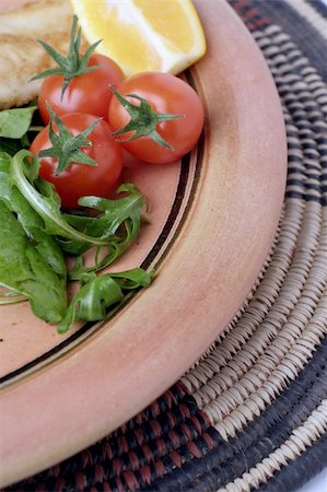 A  glazed stoneware platter or plate of salad on an African woven mat. Stockbilder - Microstock & Abonnement, Bildnummer: 400-03946947