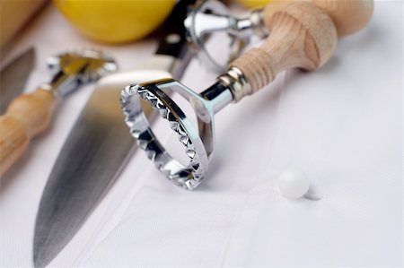 a couple of ravioli cutters and other chef's tools of trade sitting on a new chef's uniform. Could be used for training, school, hospitality courses. Foto de stock - Super Valor sin royalties y Suscripción, Código: 400-03947003