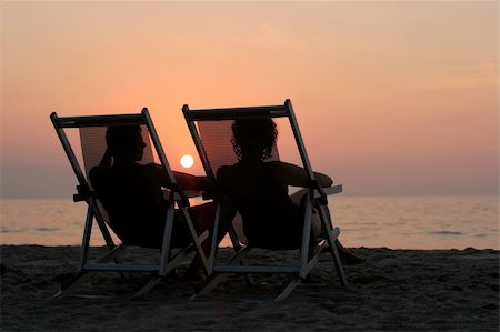 simsearch:400-03942507,k - Couple sitting in the chairs watching sunset at the beach Fotografie stock - Microstock e Abbonamento, Codice: 400-03947318