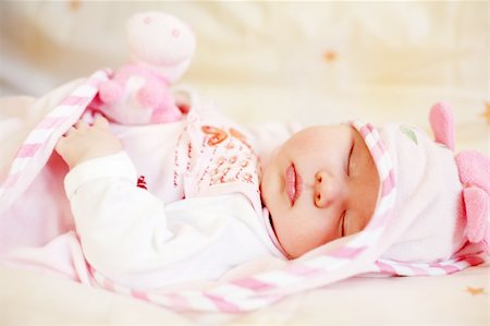 Lying sleeping baby with small teddy bear on bright background Stock Photo - Budget Royalty-Free & Subscription, Code: 400-03948919