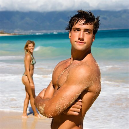 simsearch:400-03940673,k - Handsome man standing on Maui, Hawaii beach with woman in background. Stock Photo - Budget Royalty-Free & Subscription, Code: 400-03949081