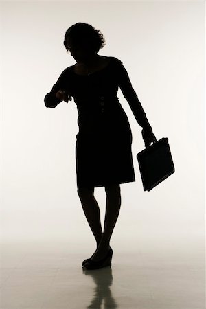 Silhouette of businesswoman holding briefcase looking at time on wristwatch. Stock Photo - Budget Royalty-Free & Subscription, Code: 400-03949160