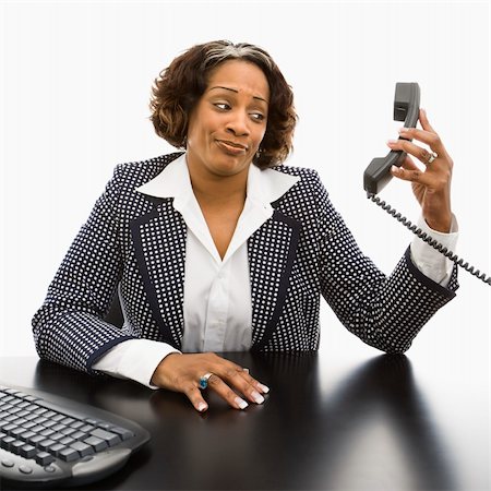 simsearch:400-04186486,k - Businesswoman sitting at desk holding telephone receiver out away from head looking with strange expression. Stock Photo - Budget Royalty-Free & Subscription, Code: 400-03949208