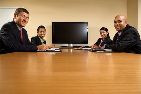 Businesspeople sitting at conference table smiling with flat screen display in background. Stock Photo - Budget Royalty-Free & Subscription, Code: 400-03949346