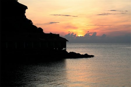 simsearch:862-08091029,k - Sunset over the ocean with tropical resort in silhouette Foto de stock - Super Valor sin royalties y Suscripción, Código: 400-03940377