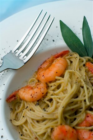 Spaghetti and prawns in a cream sauce, garnished with herbs. Served on a deep white, round bowl with wide rim sprinkled with ground pepper. View from above, shallow depth of field, portrait. Stockbilder - Microstock & Abonnement, Bildnummer: 400-03941248
