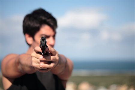 simsearch:640-01358226,k - A young, robust man, in his 20's with dark hair pointing 2 pistols to the camera. Foto de stock - Super Valor sin royalties y Suscripción, Código: 400-03941894