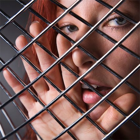 simsearch:695-05778698,k - Pretty redhead young woman face and hand behind metal pattern. Photographie de stock - Aubaine LD & Abonnement, Code: 400-03943359