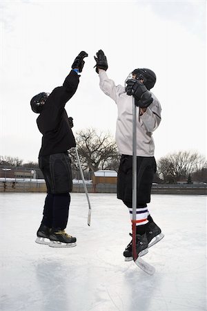 Two boys in ice hockey uniforms giving eachother high five on ice rink. Foto de stock - Super Valor sin royalties y Suscripción, Código: 400-03943518