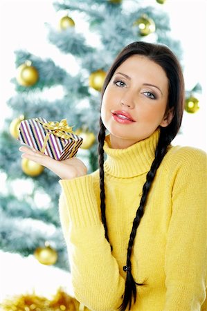 simsearch:700-02461235,k - Beautiful brunette woman next to christmas tree on white background holding boxed gift Fotografie stock - Microstock e Abbonamento, Codice: 400-03954187