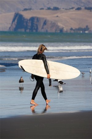 A young woman surfer walks across a beach with her surf board Stock Photo - Budget Royalty-Free & Subscription, Code: 400-03954822